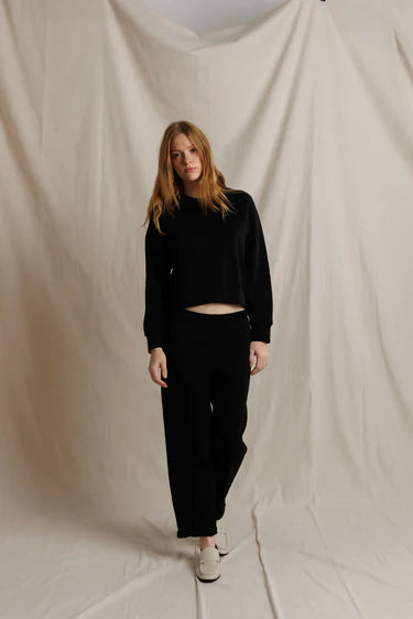 Person wearing a black outfit standing against a plain background