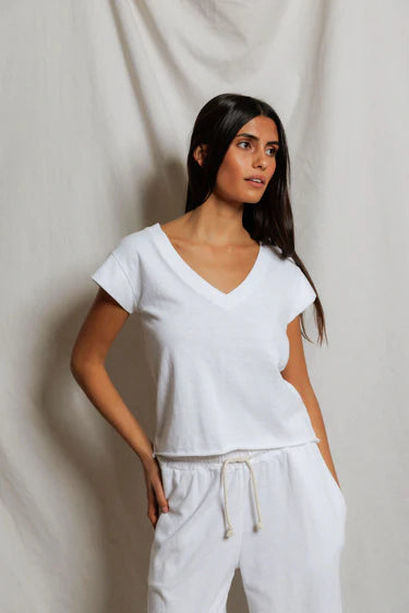Woman wearing a white top and pants against a plain background