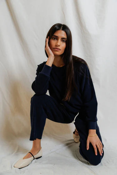 Woman in a navy blue outfit sitting on a white background