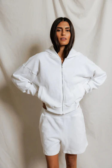 Person wearing a white hoodie and shorts set against a plain background
