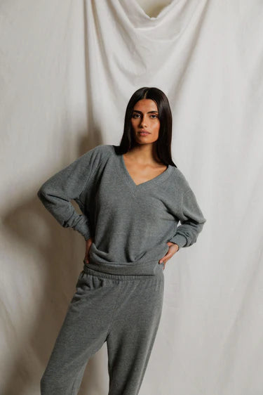 Woman wearing a gray lounge set against a plain background