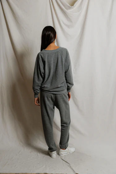 Person wearing a gray sweatshirt and pants set against a plain white background