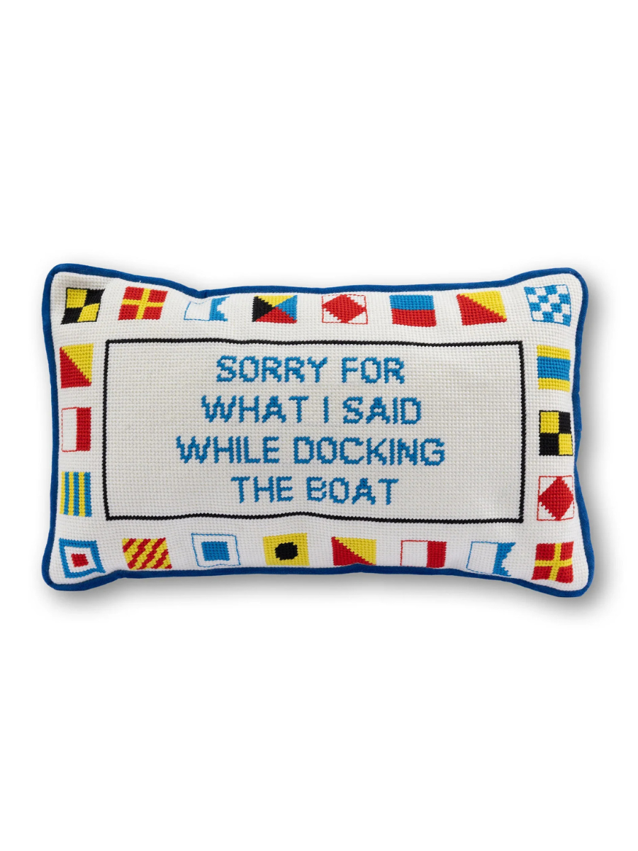 Decorative pillow with nautical flags and text on a white background