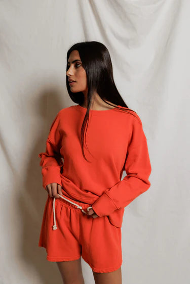 Woman wearing an orange outfit against a plain background