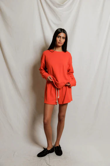 Woman wearing a bright orange outfit against a plain white background
