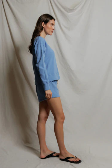 Woman wearing a blue outfit standing against a plain background