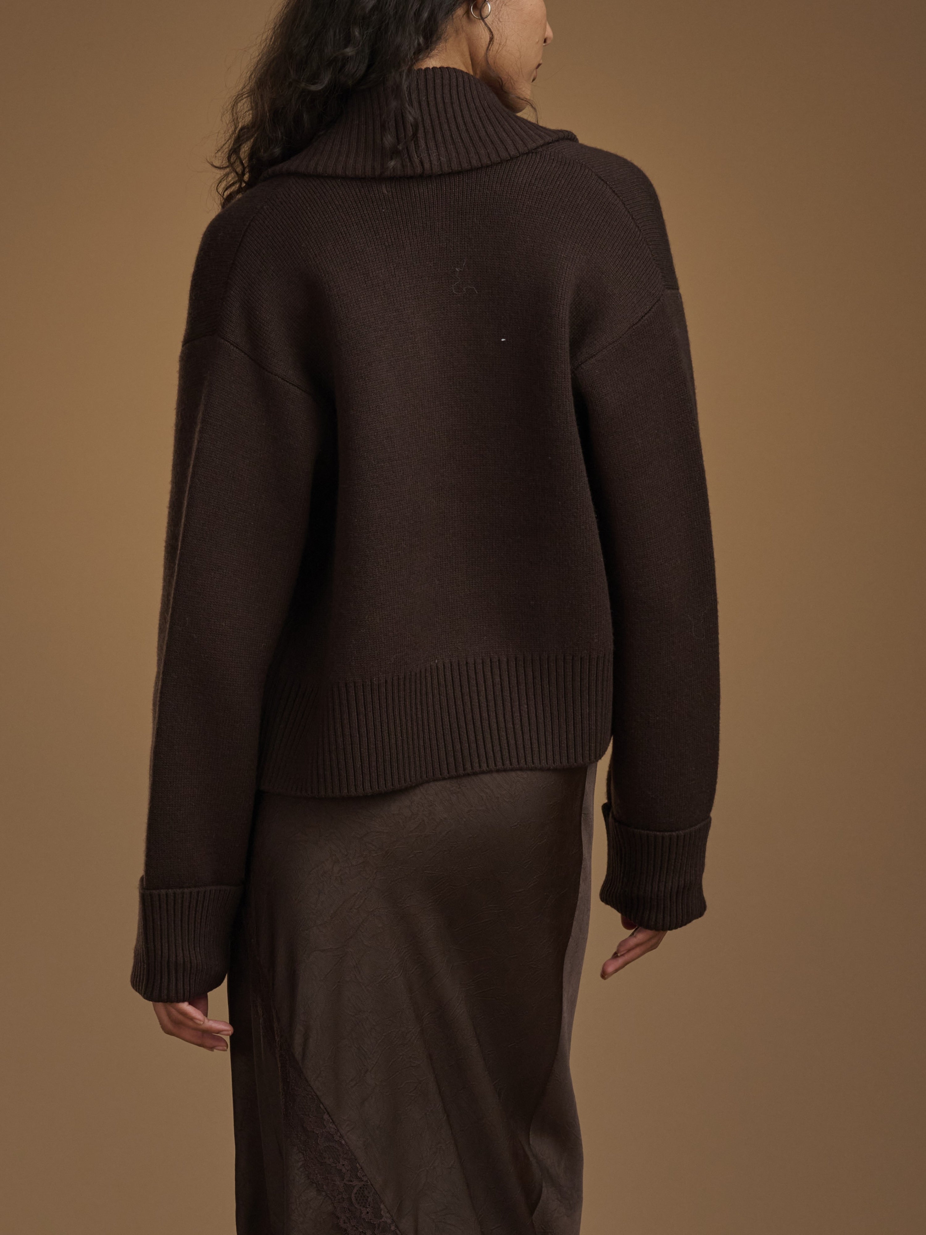 Person wearing a brown sweater against a matching background