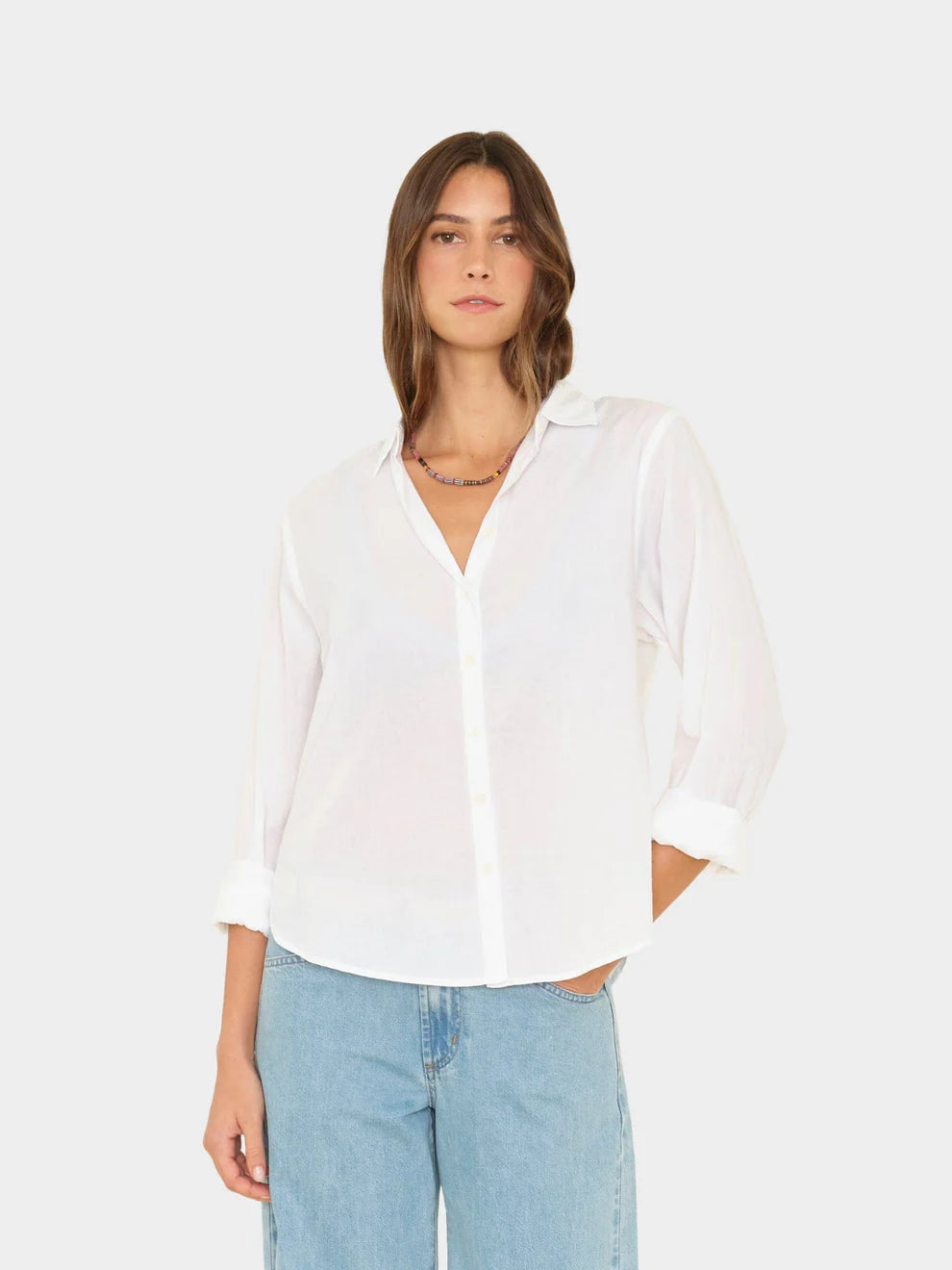 Woman wearing a white blouse and light blue jeans on a white background