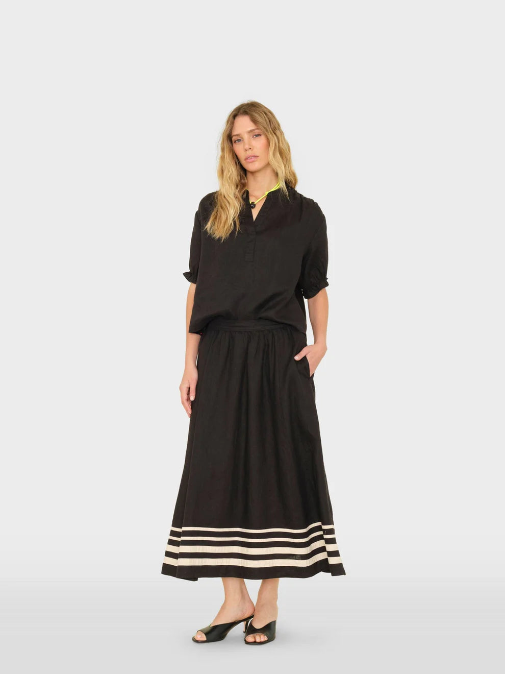 Woman wearing a black dress with white stripes on a white background