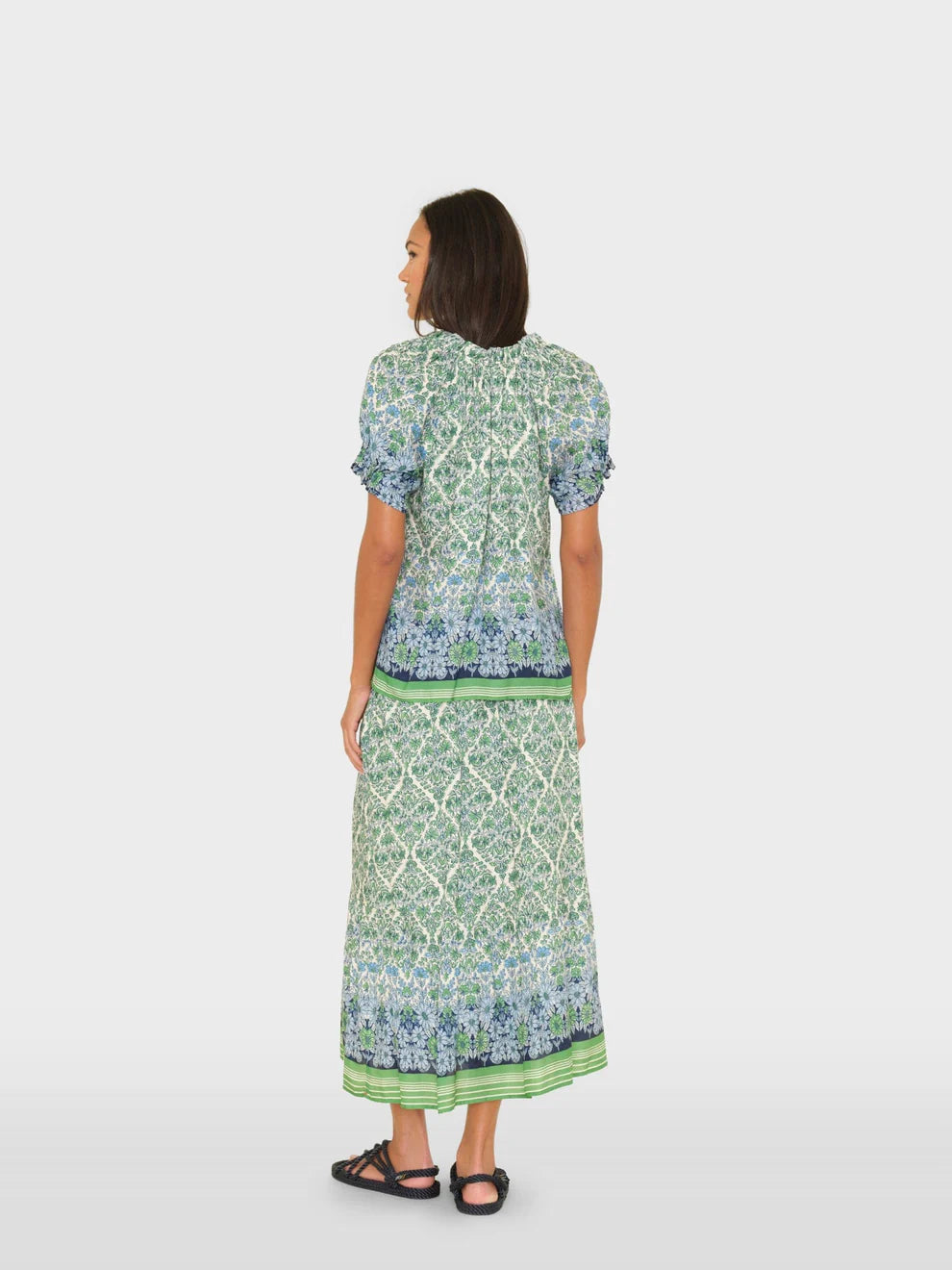 Woman wearing a green and blue patterned outfit on a white background