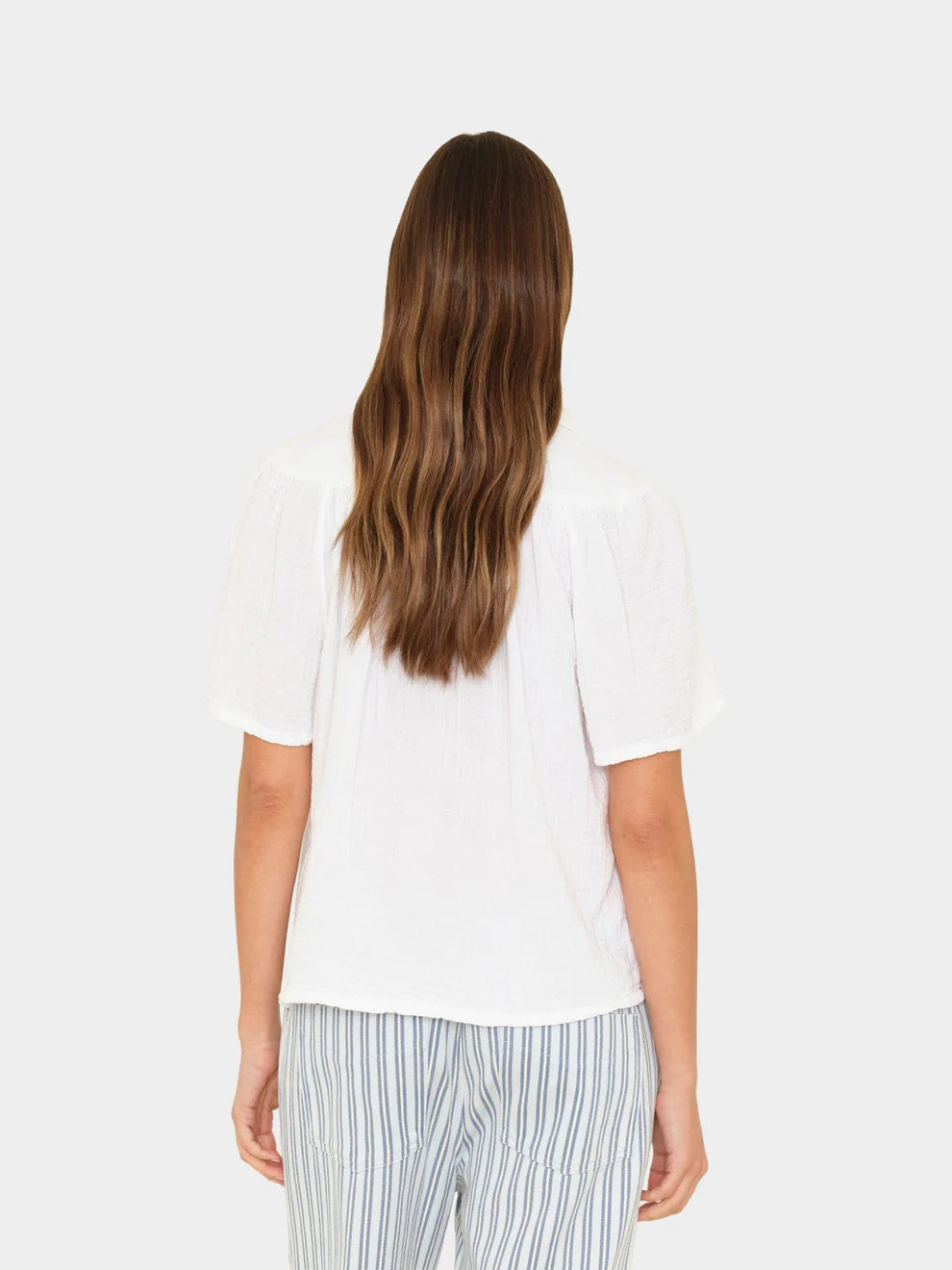 Person wearing a white top and striped pants on a white background