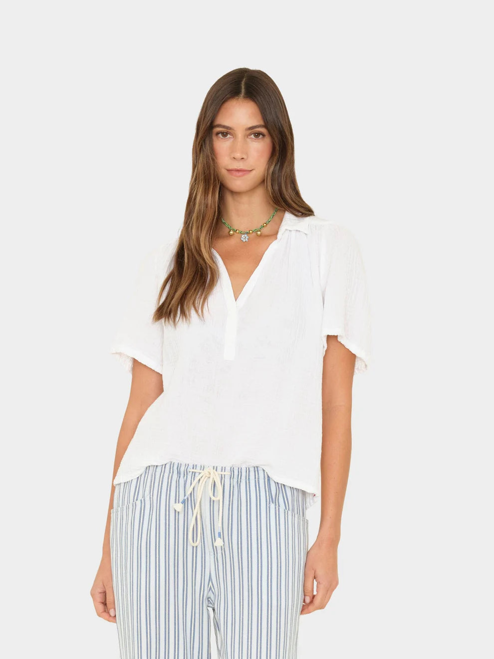 Woman wearing a white top and striped pants on a white background