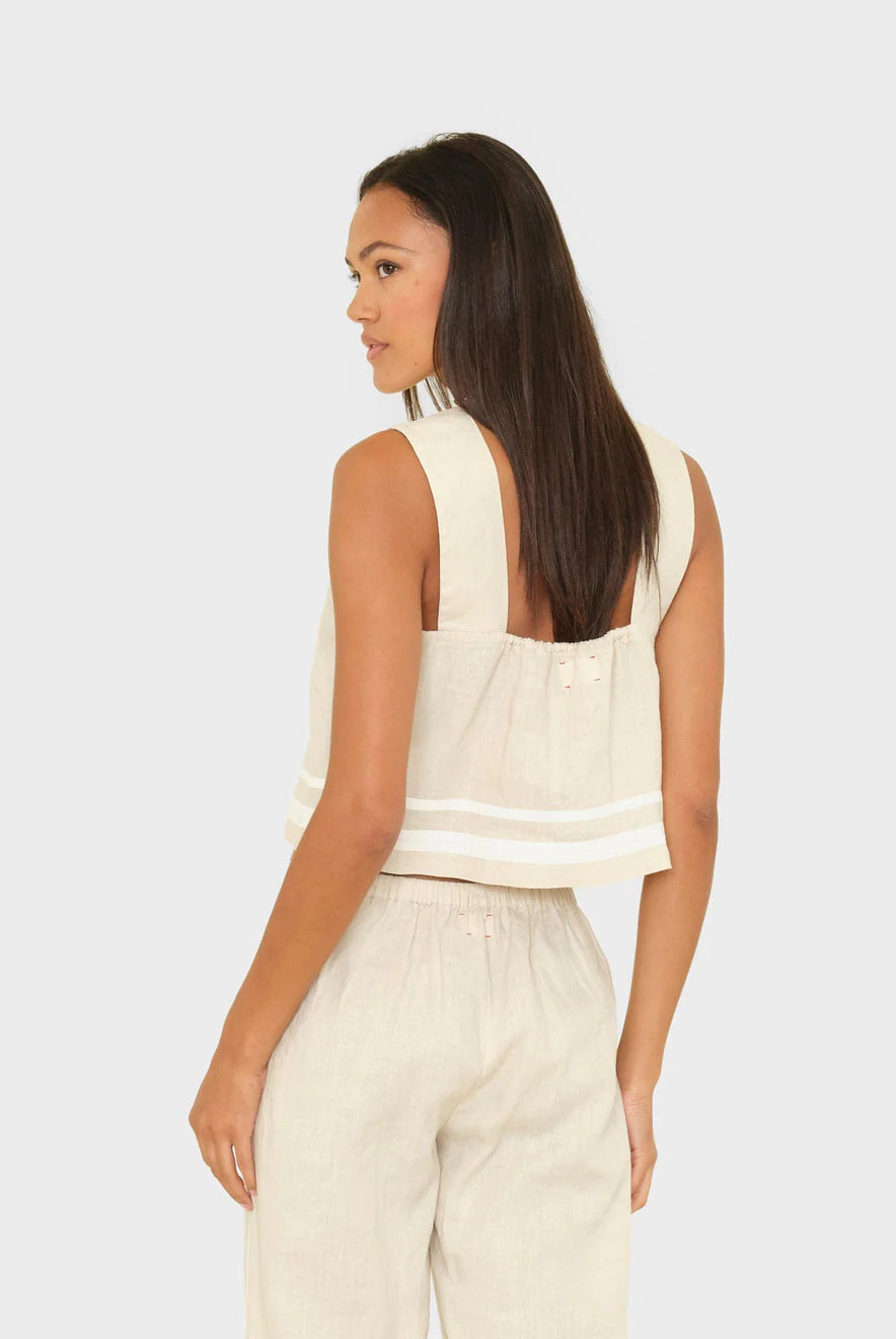 Woman wearing a sleeveless beige top and pants on a white background