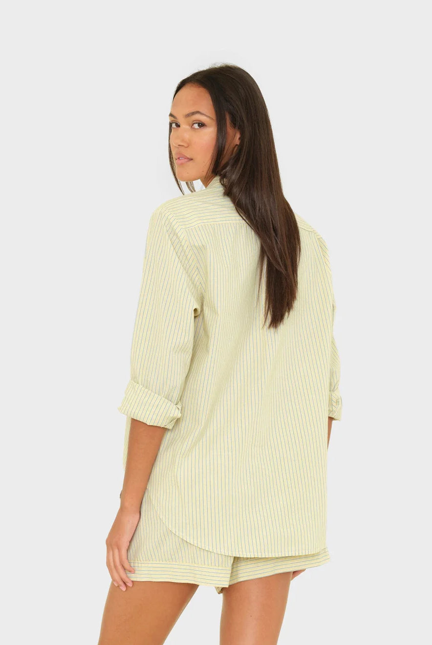 Woman wearing a light green ribbed top and shorts on a white background