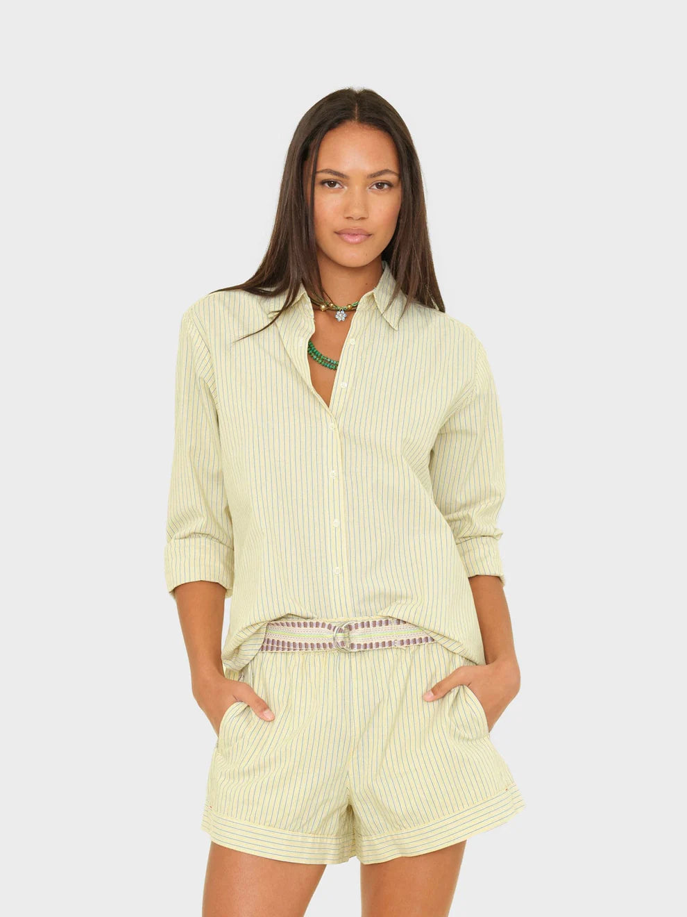 Woman wearing a light green striped shirt and shorts on a white background