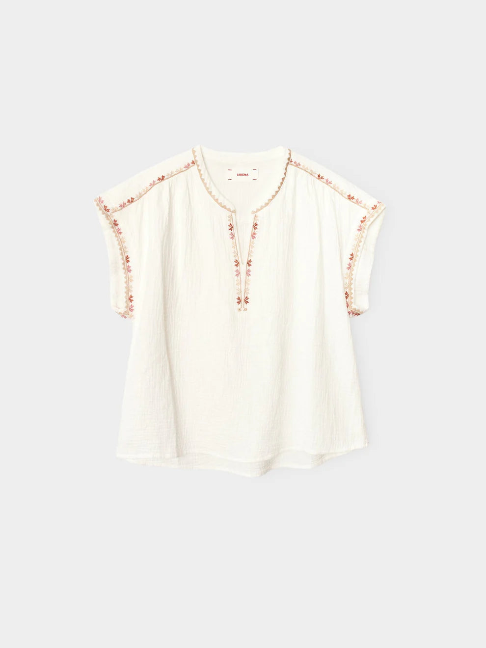 White blouse with floral embellishments on a light gray background