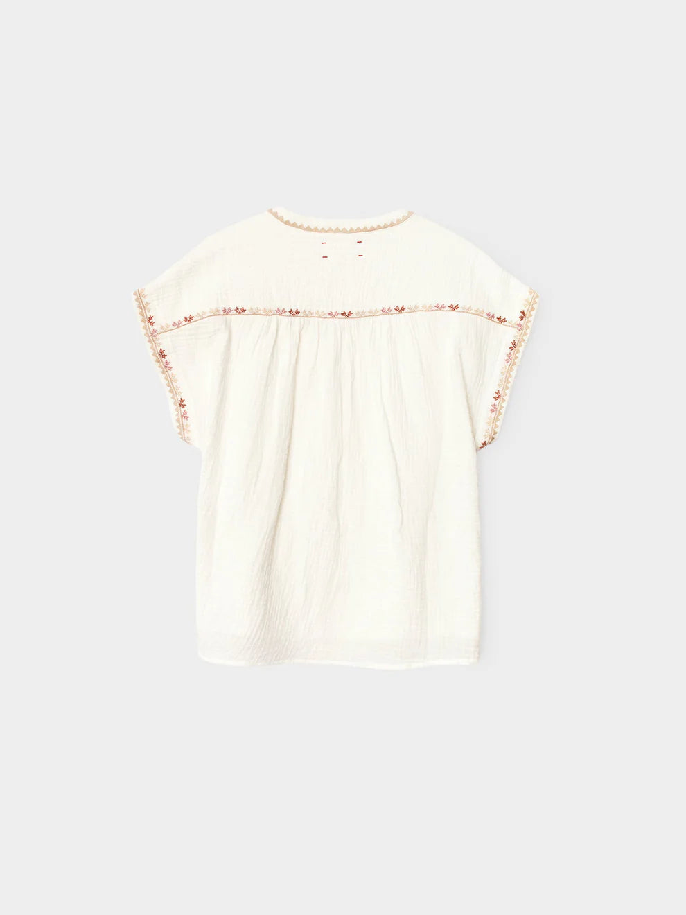 White blouse with floral details on a light gray background