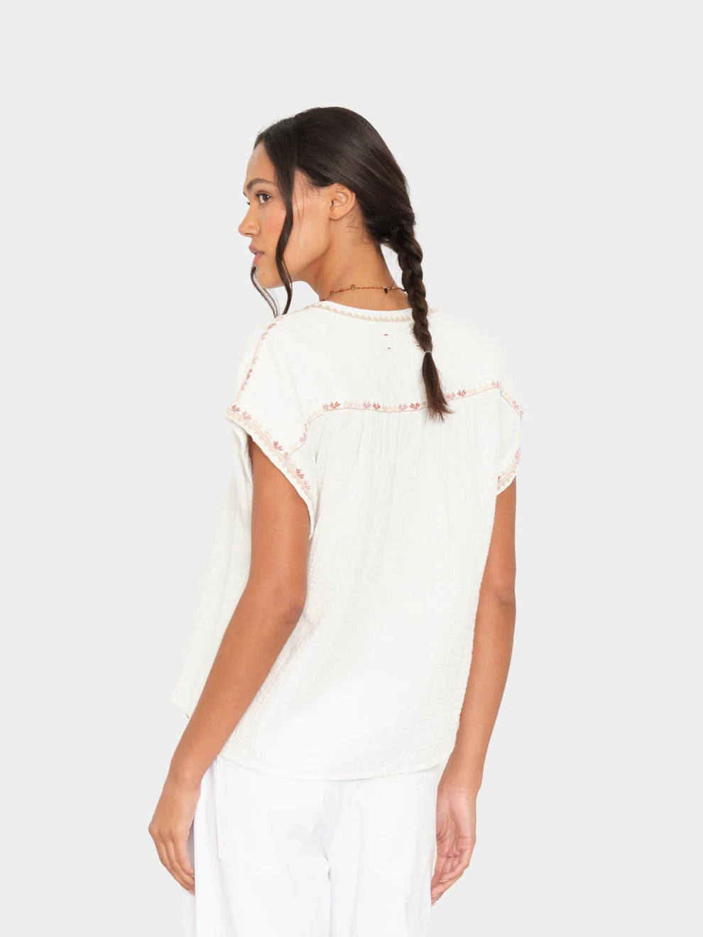Woman wearing a white lace top against a plain background