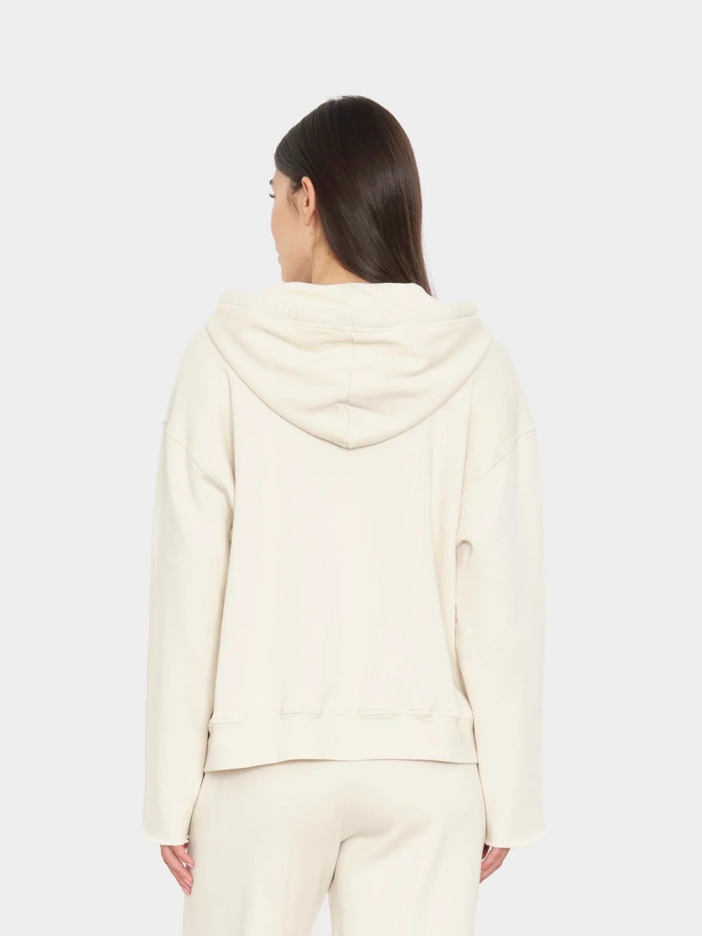 Person wearing a cream-colored hoodie and pants on a white background
