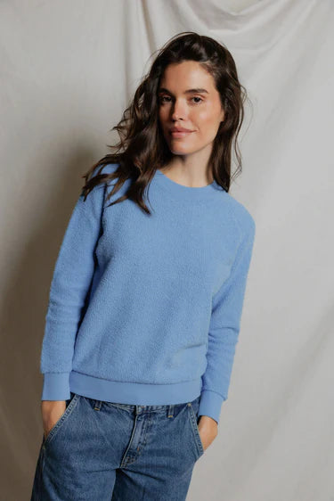 Woman wearing a blue sweater and jeans against a plain background