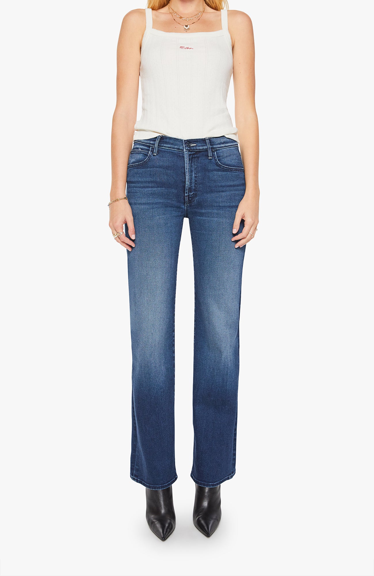 Woman wearing blue jeans and a white tank top on a white background