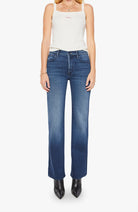Woman wearing blue jeans and a white tank top on a white background