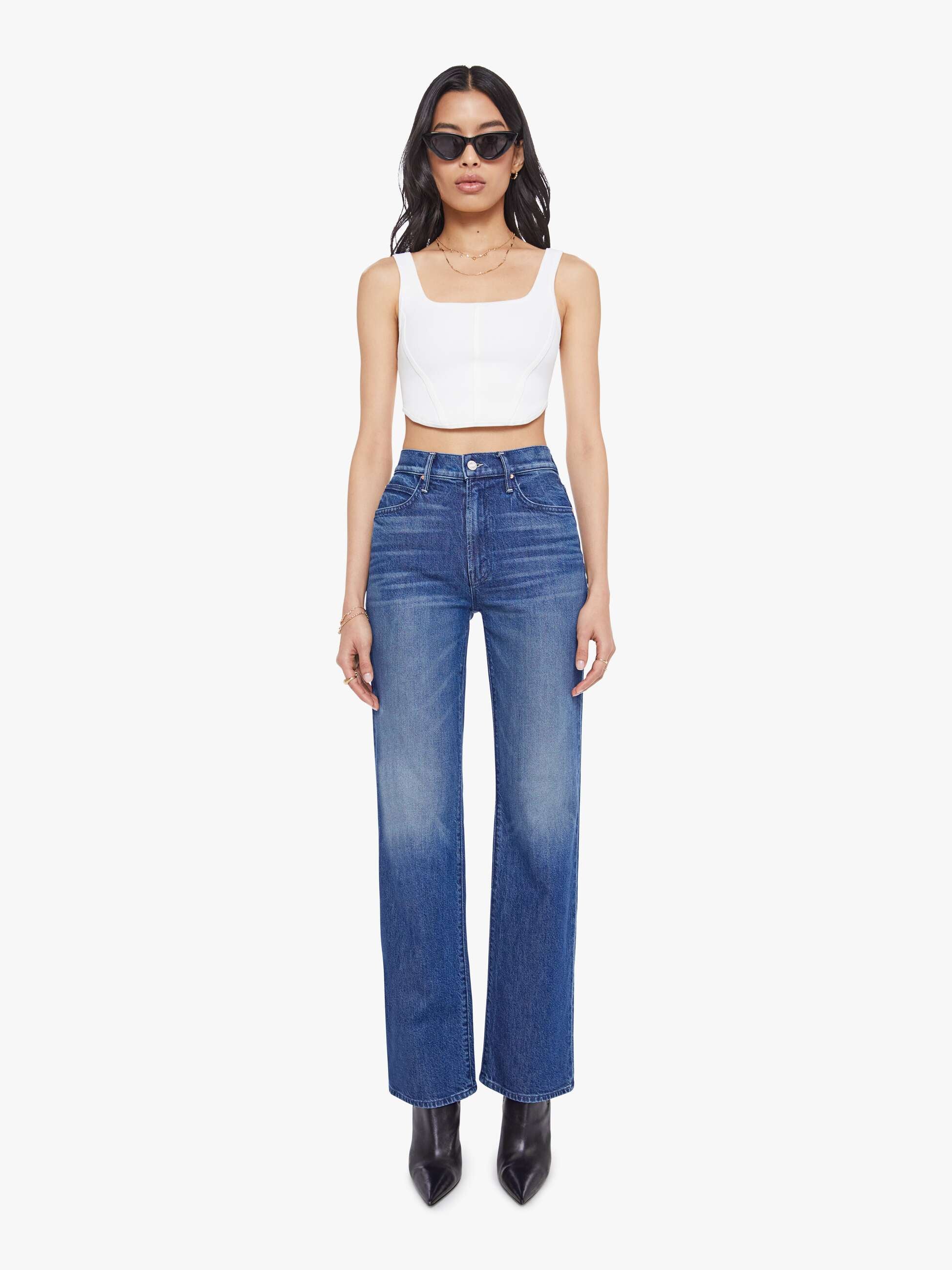 Woman wearing a white top and blue jeans on a white background