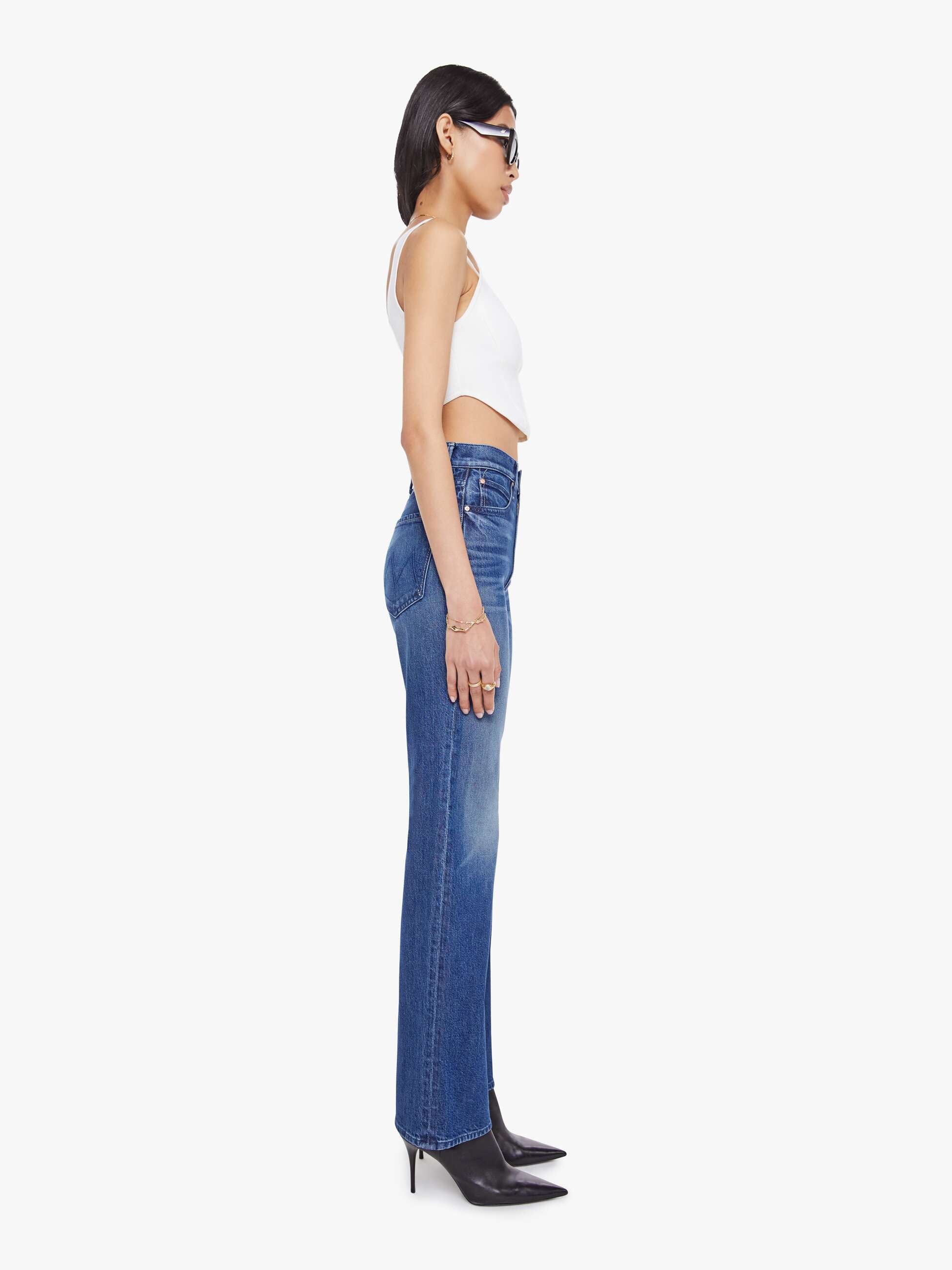 Woman wearing blue jeans and a white top on a white background