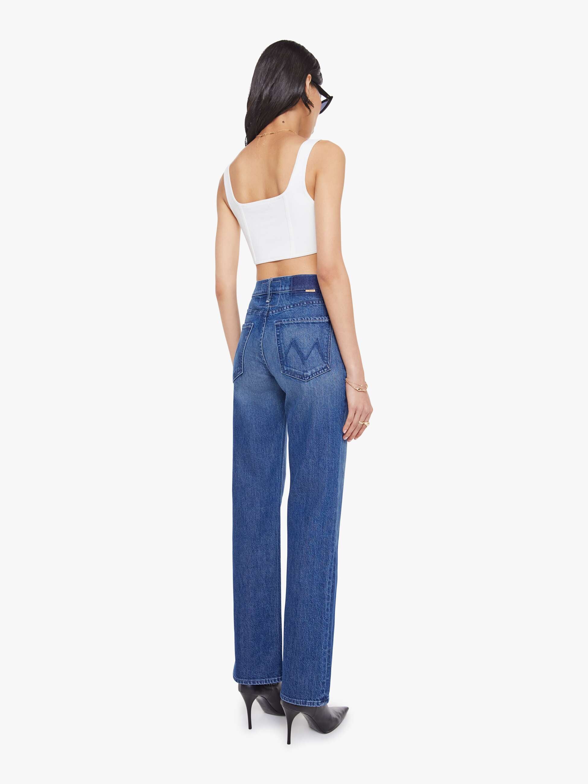 Woman wearing blue jeans and a white top on a white background