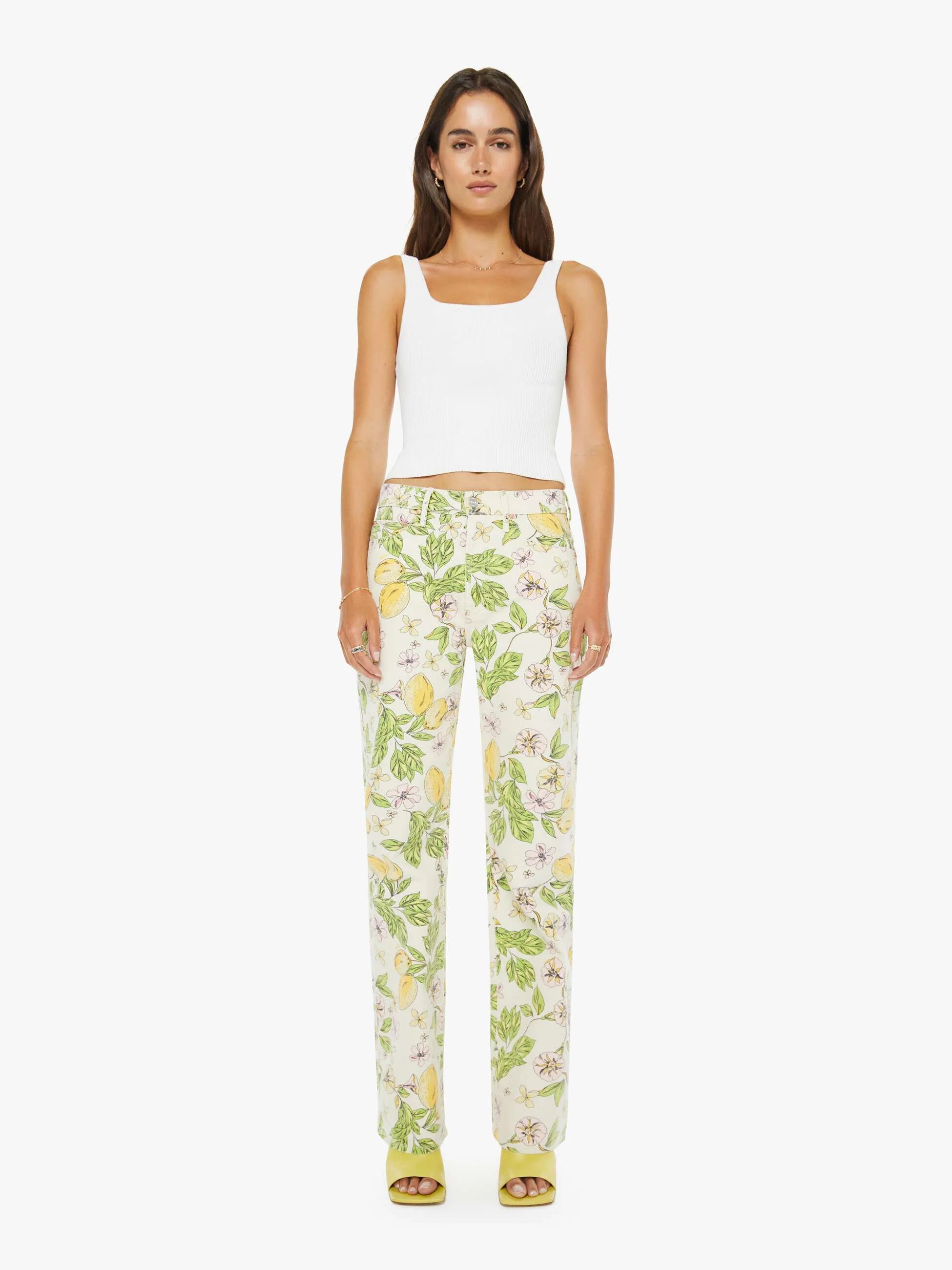 Woman wearing a white sleeveless top and floral pants on a white background