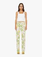 Woman wearing a white sleeveless top and floral pants on a white background