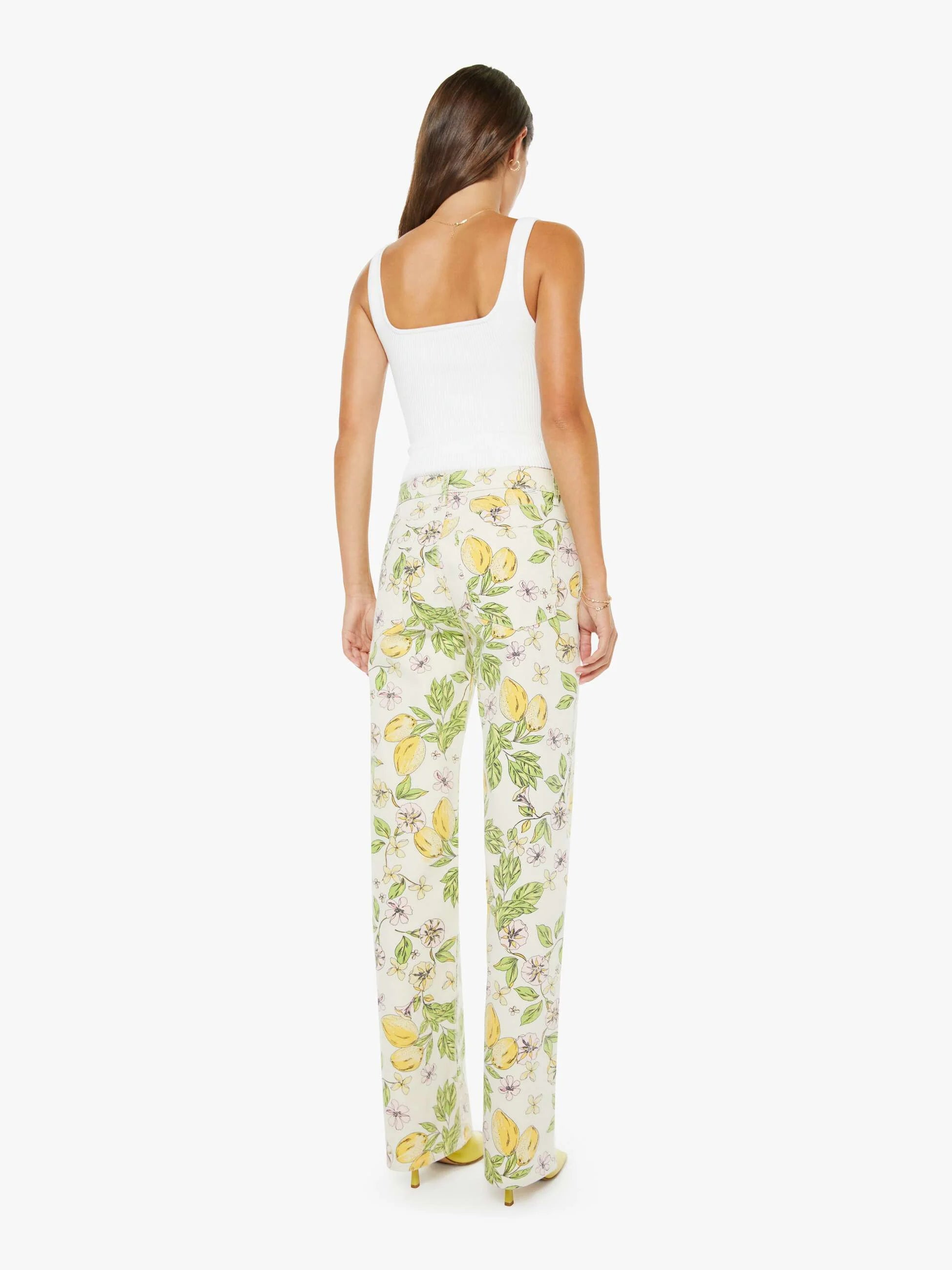 Woman wearing a white tank top and floral pants on a white background