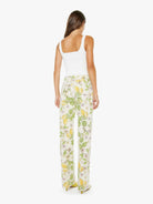 Woman wearing a white tank top and floral pants on a white background