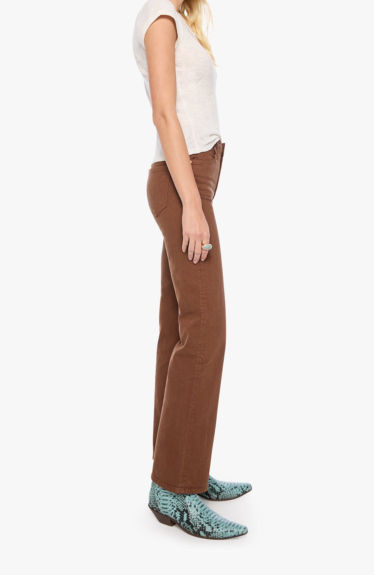 A side-profile view of a model wearing brown wide-leg pants, a white sleeveless top, and green snakeskin-patterned boots against a plain white background.