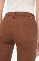 Rear view of a person wearing brown high-waisted jeans with a belt loop and back pocket details, paired with a light heather gray top.