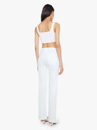 Woman wearing a white sleeveless top and pants on a white background