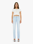 Woman wearing a white top and light blue jeans on a white background