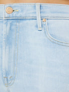 Close-up of light blue denim jeans with button and zipper details.