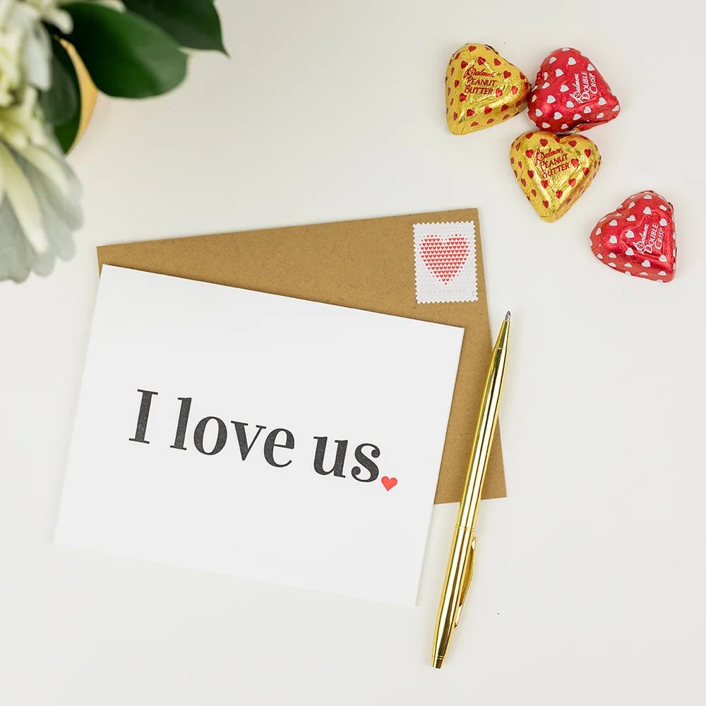 A white greeting card with the words 'I love us.' printed in black, placed on top of a brown envelope.