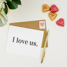 A white greeting card with the words 'I love us.' printed in black, placed on top of a brown envelope.