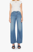 Woman wearing blue wide-leg jeans and a white top on a white background