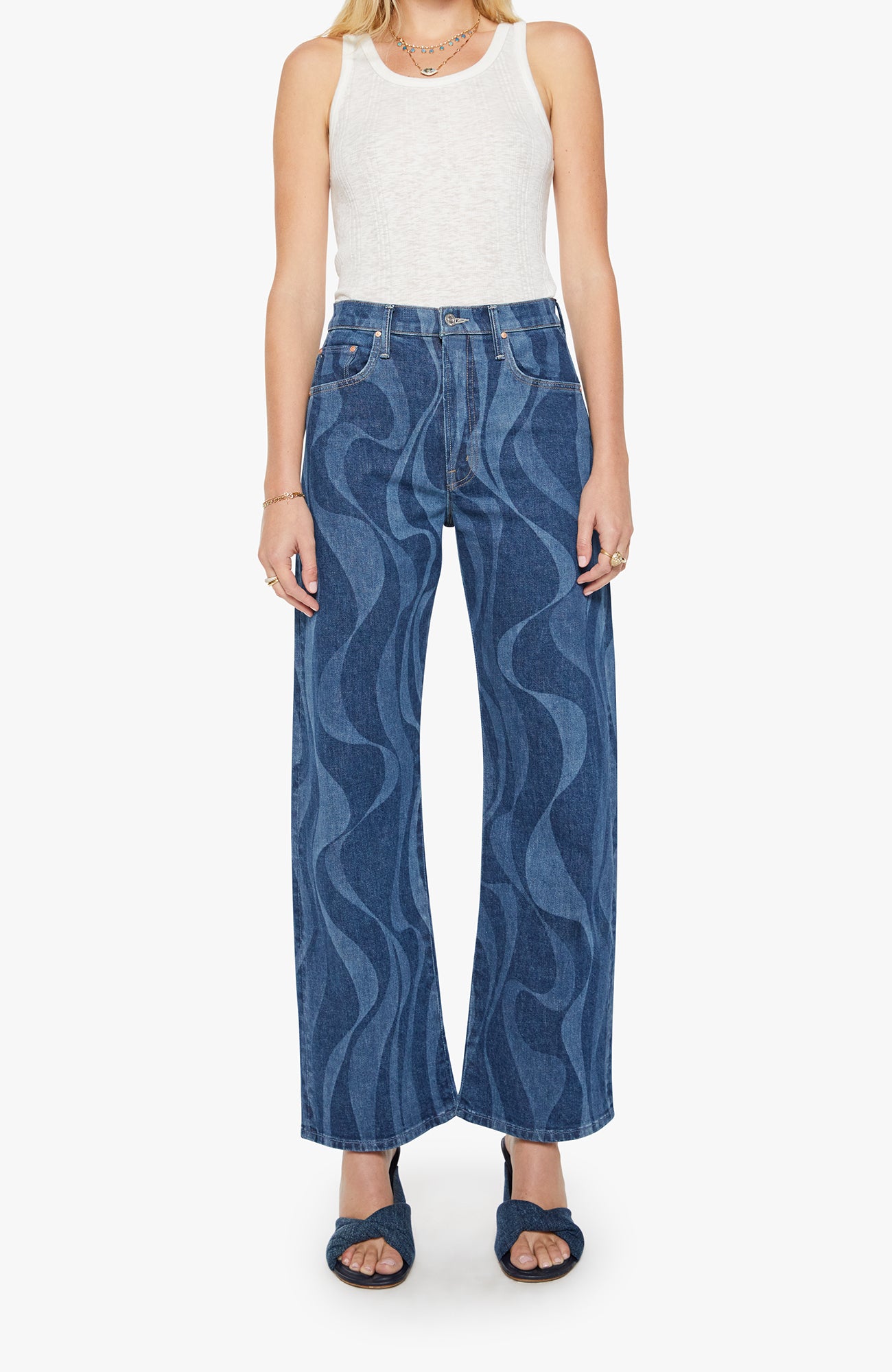 Woman wearing blue patterned jeans and a white top on a white background