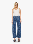 Woman wearing blue patterned jeans and a white top on a white background