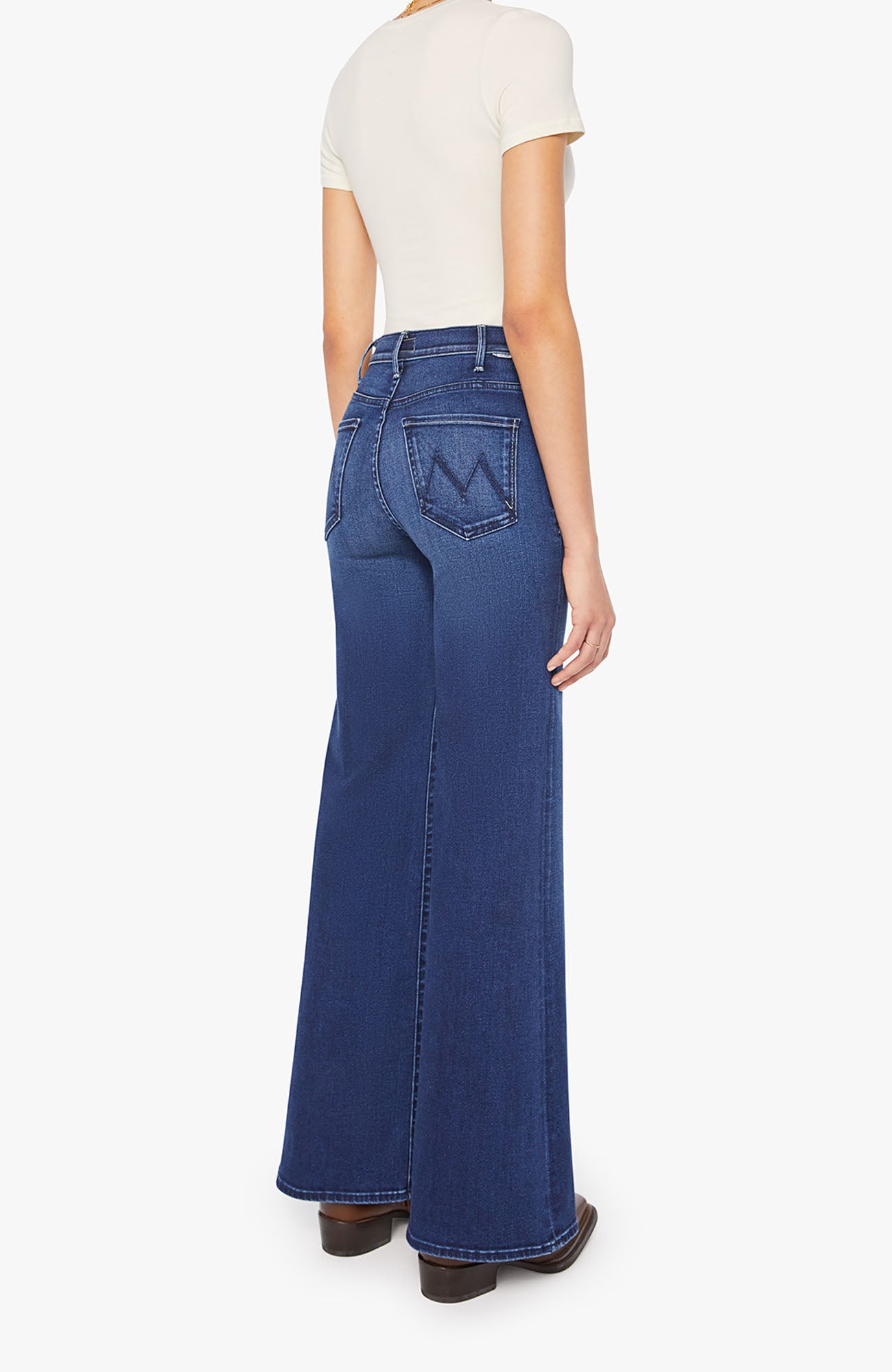 Person wearing blue flared jeans on a white background