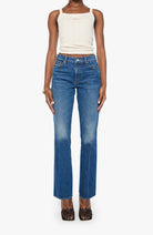 Person wearing a white tank top and blue jeans on a white background