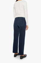 Person wearing a white sweater and dark blue jeans on a white background