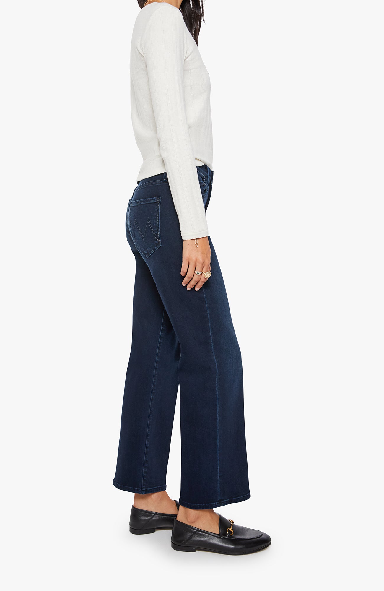 Person wearing navy wide-leg jeans and a white top on a white background
