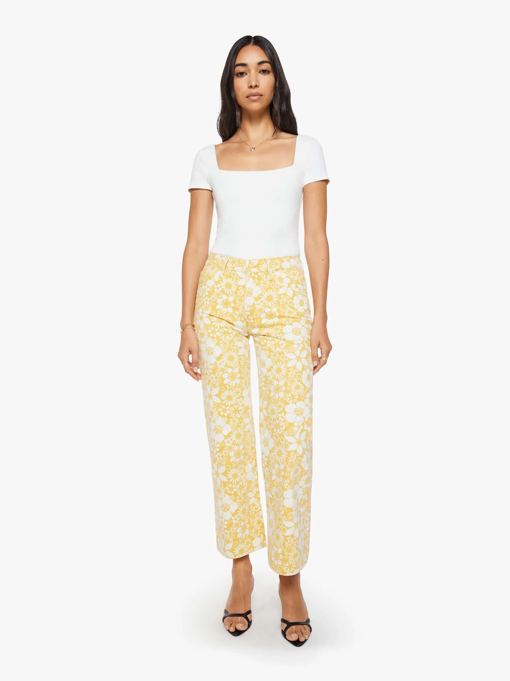 Woman wearing a white top and yellow floral pants on a white background
