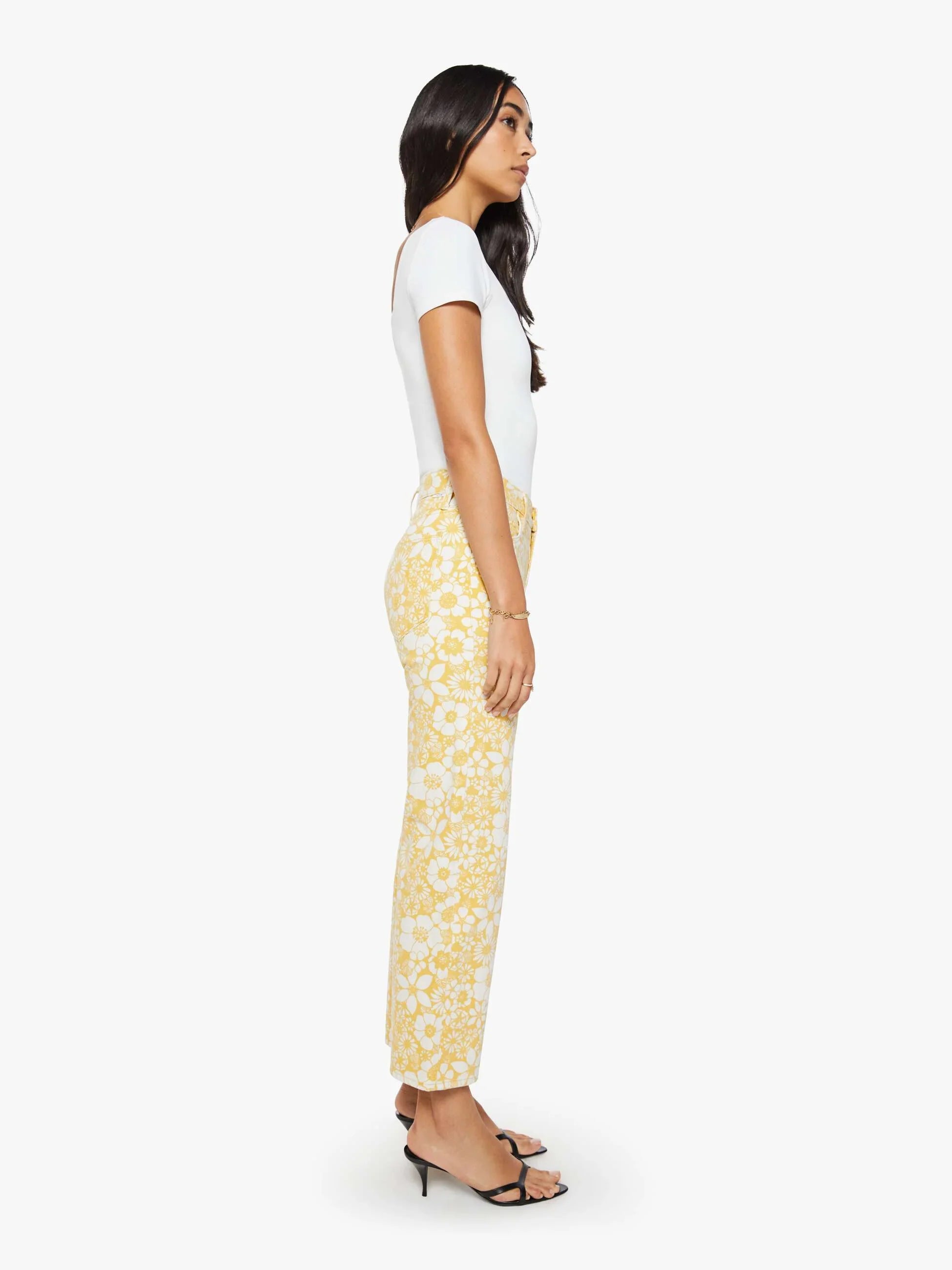 Woman wearing a white top and yellow floral pants on a white background