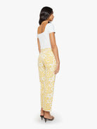 Woman wearing a white top and yellow floral pants on a white background